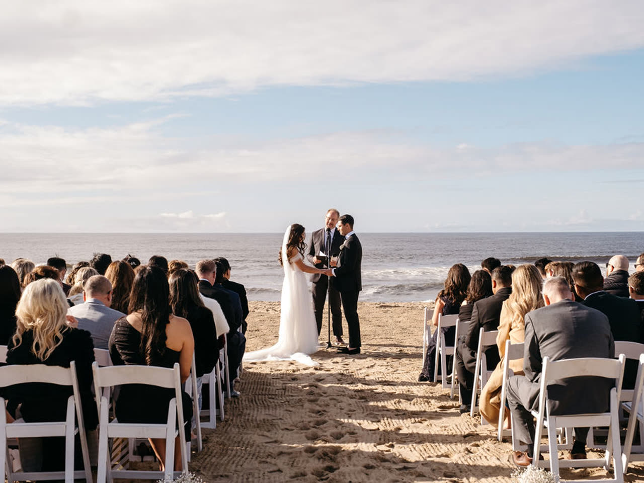 A beachfront wedding ceremony where wind and open sand shape the setup