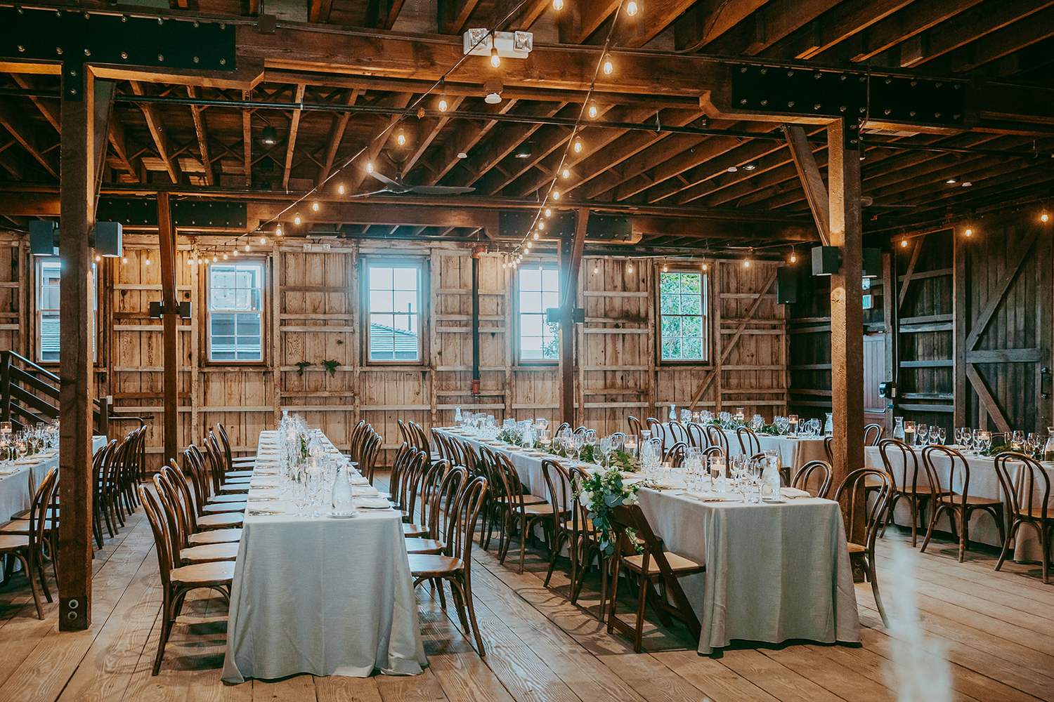 The Barns at Cooper Molera set for a wedding dinner, long tables under the barn's high timber ceiling