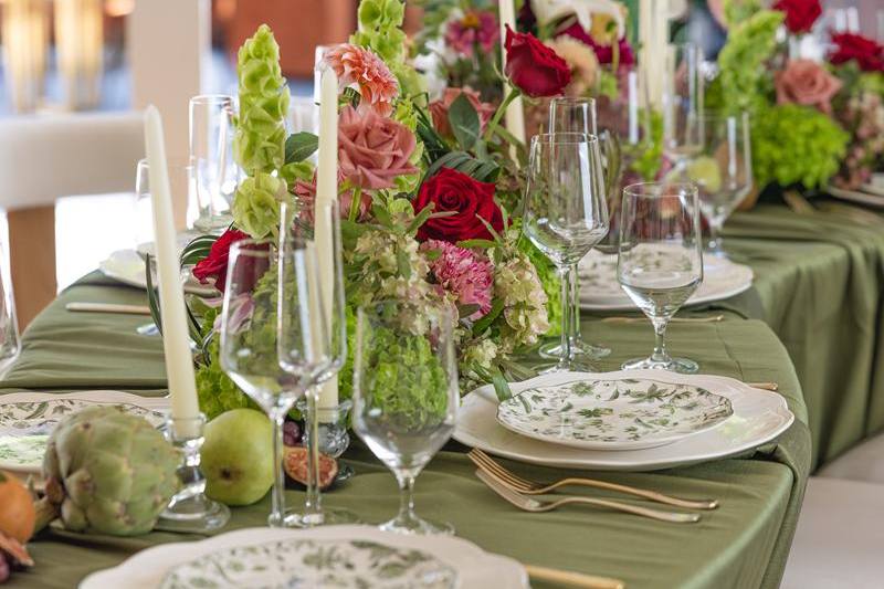 A wedding table at La Mirada set with green linen, garden florals, and candles