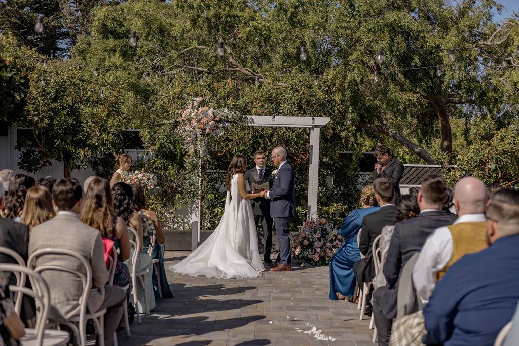 A wedding ceremony underway in the Perry House courtyard, guests seated under the trees