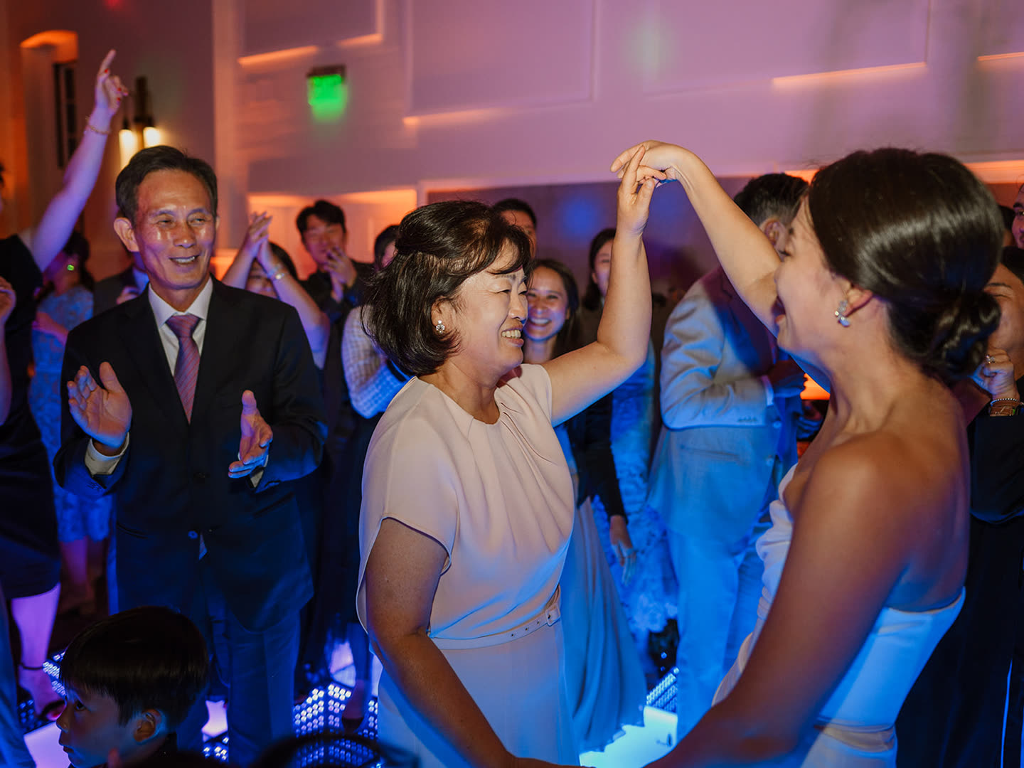 A mother and the bride dancing together on a full floor