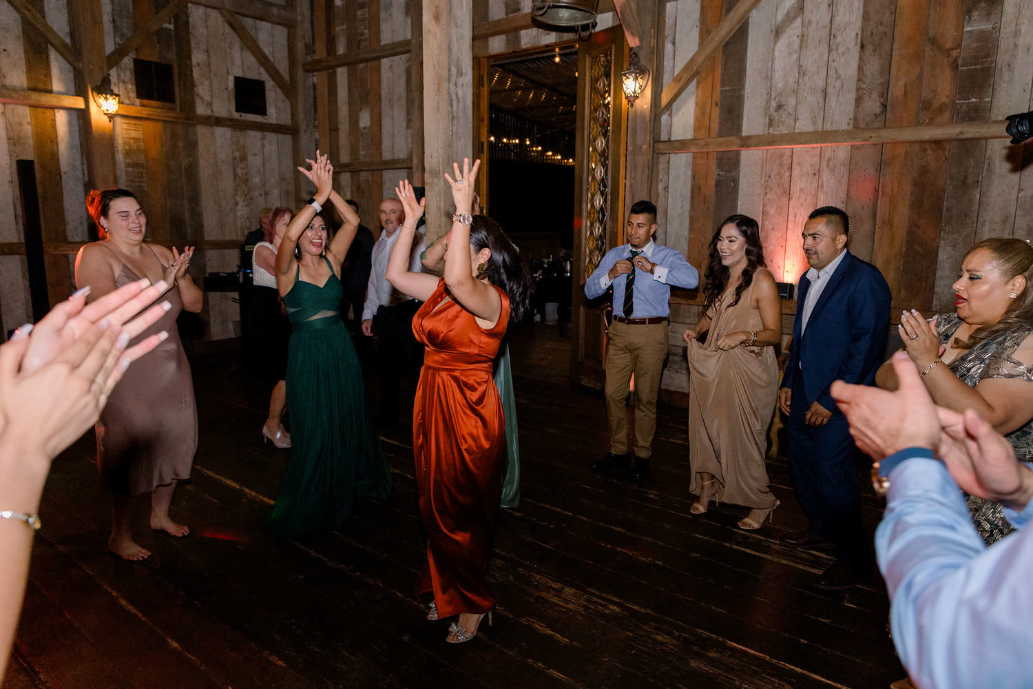 Guests of every age dancing inside the lodge, timber walls and a wood floor around them