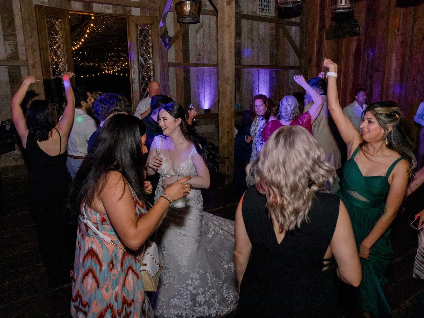 A packed dance floor inside the lodge, the bride at the center with friends dancing around her